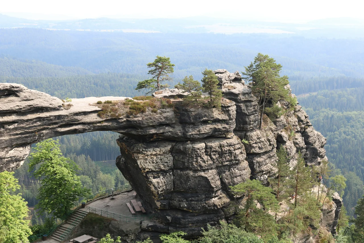 Pískovcová Pravčická brána nad lesnatou krajinou Českého Švýcarska.